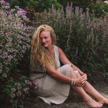 The Green Goddess in her medicinal herb garden surrounded by flowering herbs.