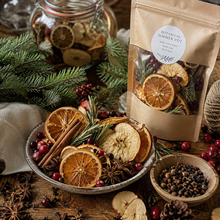 Botanical Christmas simmer pot with dried oranges, apples, cranberries, cinnamon, warming spices, and evergreen branches.